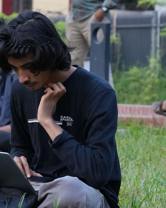 Meer working on a laptop in a park in Chittagong